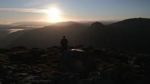 An explorer on a mountain summit with his tent at sunrise Stockbeeldmateriaal 245795361