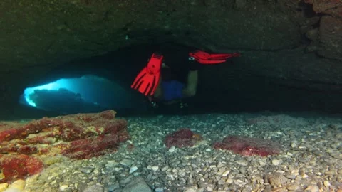 Explorer scuba diving in the cave. Rocks and sand in the tunnel and scuba diver Stock Footage 294712414
