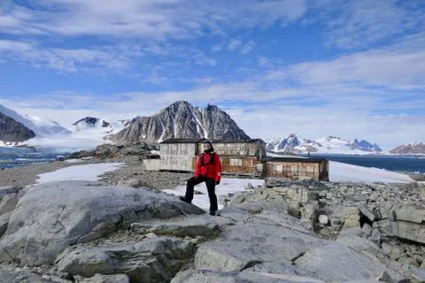 Explorer standing before antarctic expedition base with mountain, Antarctica Stock Photos