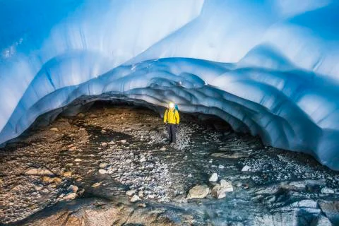 Explorer standing under glacier in cave. Stock Photos