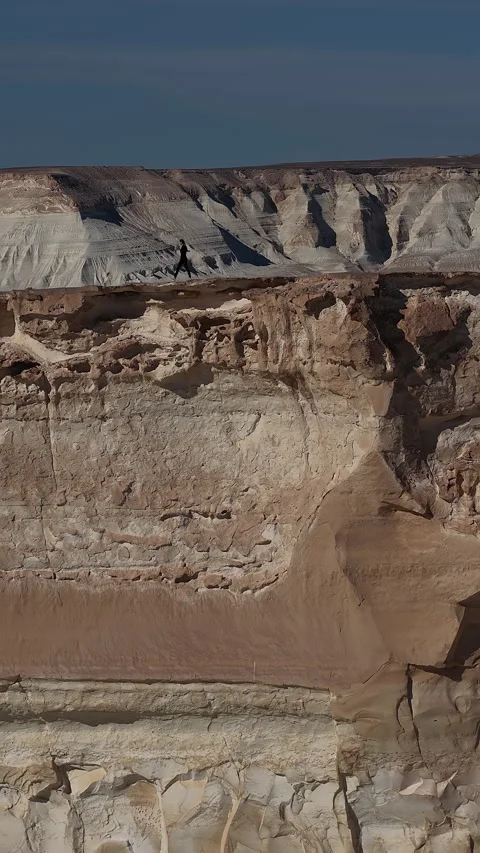 Explorer walking along the edge of a massive canyon cliff, Bozjyra, Mangystau Stock Footage 322826905