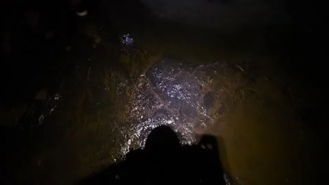 Explorer walking through a dark cave with flashlight Vídeos de archivo 334934329