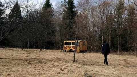 Explorer Walking Toward Abandoned Yellow Rail Car in Mountain Meadow Stock Footage 334330016