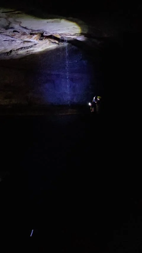 Explorers in cave with flashlights and dripping water during underground tour 스톡 동영상 310142903