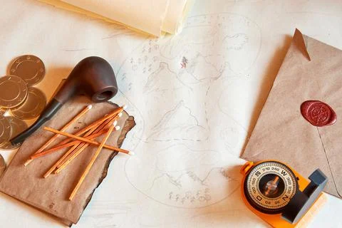 Explorer's desk background with an ancient treasure map, smoking pipe, compass Stock Photos