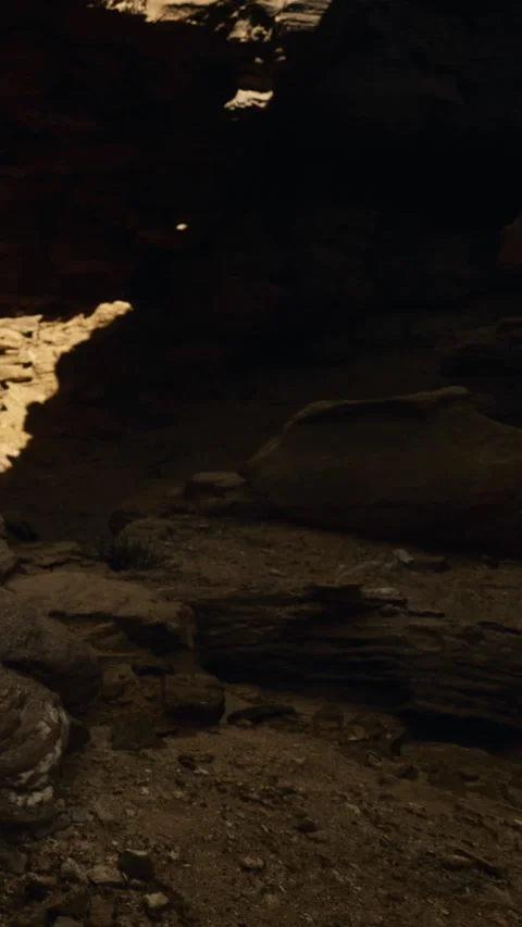 Explorers venture into a dim cave, surrounded by rough stones and soft sand Stock Footage 334252664