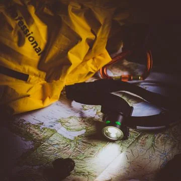 Exploring Adventure Hiking Concept. Looking navigation map in tent at night u Stock Photos