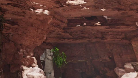 Exploring a cave with natural formations and greenery in a rocky setting Stock Footage 337873489