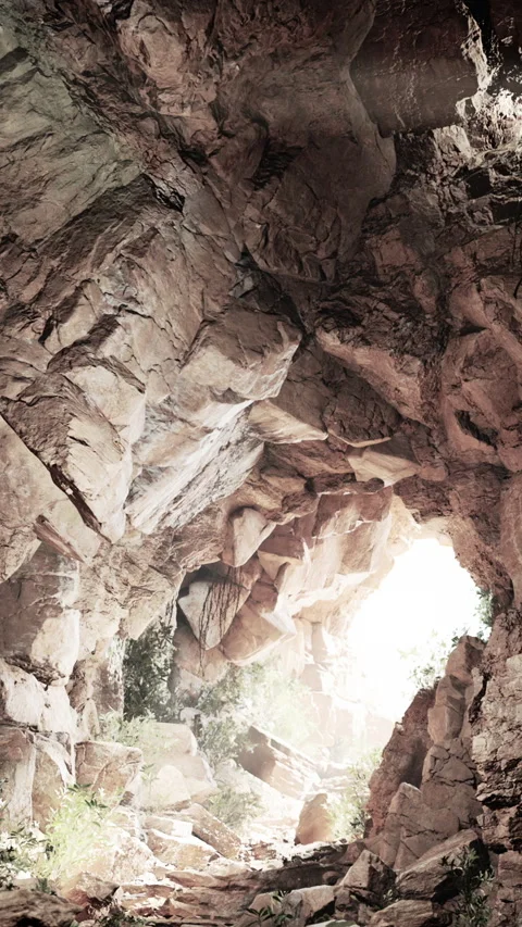 Exploring a cave with rocks and light shining through the entrance Stock Footage 339508710