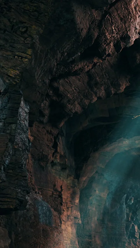 Exploring a cave with rocky walls and light beams in a dark setting Stock Footage 335694153