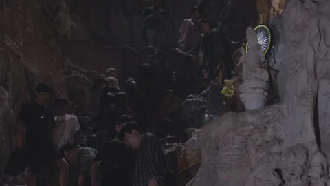 Exploring a cave temple with visitors descending steep stone steps at twilight Video stock 312242894