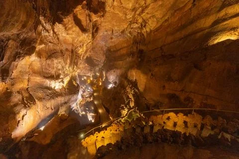 Exploring a cave with winding paths and lit formations in a natural underground Stock Photos
