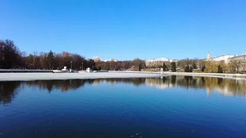 Exploring a clear lake with trees around and buildings in the distance on a brig Stock Footage 331815676