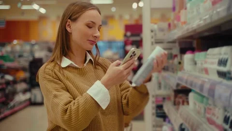 Exploring cosmetics aisles while scanning beauty products in a retail store 스톡 동영상 293673761