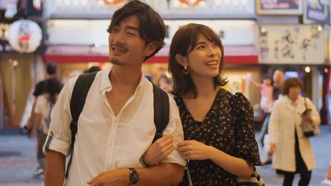Exploring couple walking through Osaka streets experiencing Japanese culture  Vídeo Stock 111401997