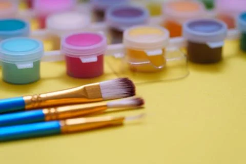 Exploring creativity with paint and brushes on a yellow surface in a bright.. Stockfoto's