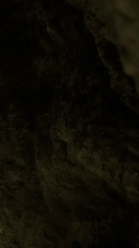 Exploring the dark cave and its rocky textures under dim lighting Stock Footage 332227795