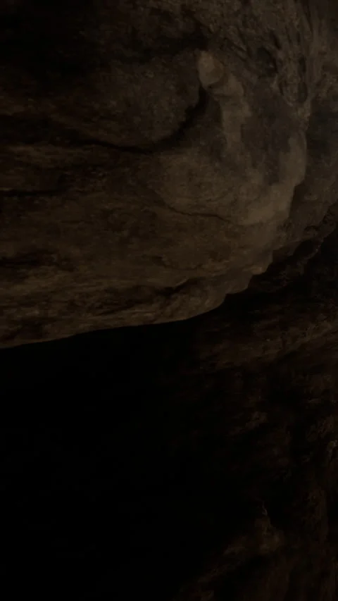 Exploring a dark cave with rugged rocks and uneven surfaces at night Stock Footage 339414906