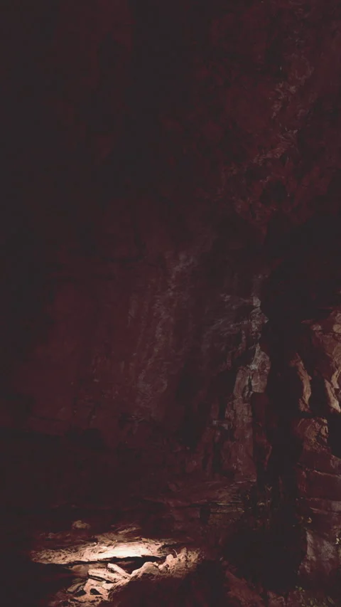 Exploring a dark cave with stone formations and minimal light source Stock Footage 341987303
