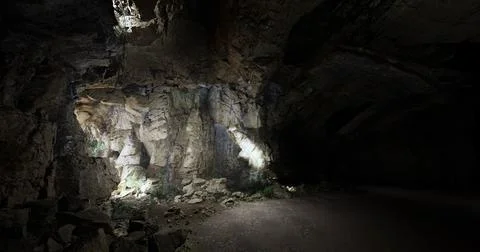 Exploring the dark depths of an underground cavern illuminated by lights Ilustración de archivo