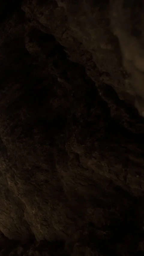 Exploring the depths of a dark cave with rocky walls and limited light Stock Footage 339393259