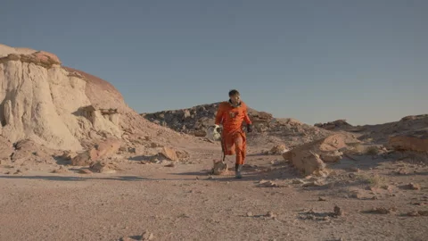 Exploring a desert landscape in an astronaut suit and helmet during sunset Stock Footage 288831324