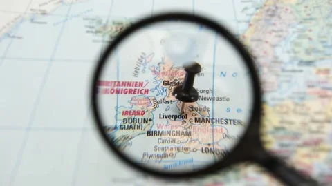 Exploring a destination on a paper map of Liverpool with a magnifying glass Stock Footage 340078926