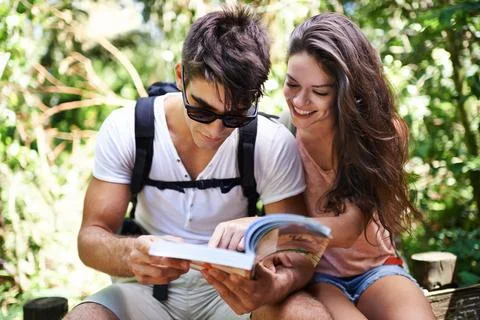 Exploring the forest. a young couple looking at a guidebook while out hiking. Stockfoto's