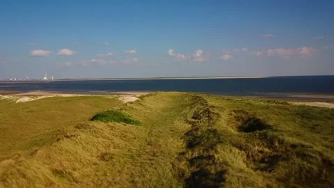 Exploring grassy hills and calm waters at the coast during sunset Stock Footage 339940643