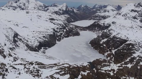 Exploring a large frozen lake surrounded by mountains in a snowy landscape Stock Footage 334774649