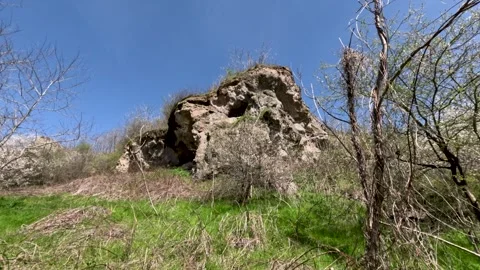 Exploring a large rock formation in a grassy area on a sunny day Stockbeeldmateriaal 334302894