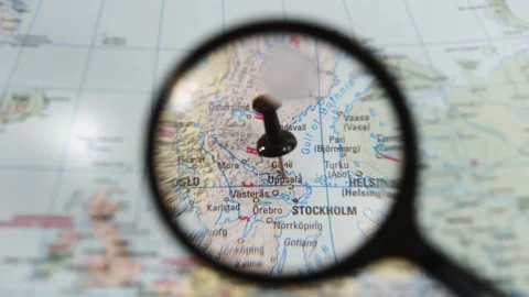 Exploring a location on a paper map of Uppsala with a magnifying glass Stock Footage 340078870