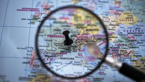 Exploring locations on a map with a magnifying glass Stock Photos