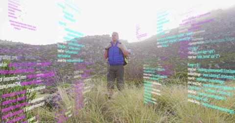 Exploring man in puffer vest with backpack on meadow with purple wildflowers, Foto stock