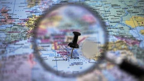 Exploring a map with a magnifying glass and a pin on Athens Stock Photos