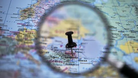 Exploring a map with a magnifying glass and a pin in Chisinau Stock Photos