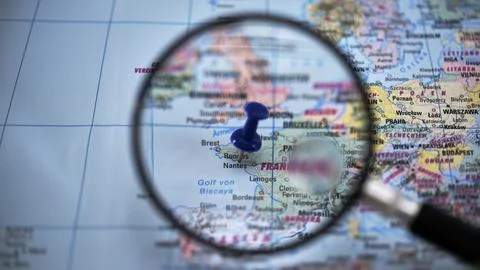 Exploring a map with a magnifying glass and a blue pushpin in Nantes Stock Photos