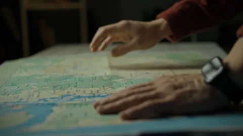 Exploring a map to plan the next adventure in a dimly lit room Stock Footage 297704785