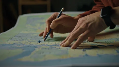 Exploring a map while planning a journey with pins and a pencil for precise Stock Footage 301346184