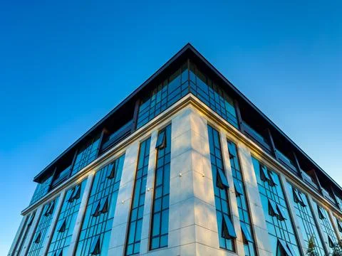 Exploring modern architecture at dawn with reflections on a glass facade in.. Stock Photos