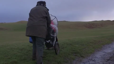 Exploring the muddy trails with a stroller and a dog in the countryside Stock Footage 325807607
