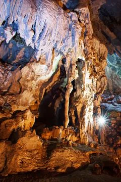 Exploring mystic limestone cave with torch. Stock Photos