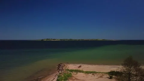 Exploring a quiet beach with clear water and distant green land on a sunny da Stock Footage 339932777