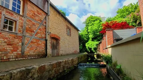 Exploring a quiet pathway alongside a stream near historic buildings in a g.. Stock-Footage 347460257