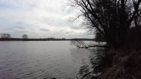 Exploring the riverbank with cloudy skies and flowing water in a quiet natural s Stock-Footage 333440160