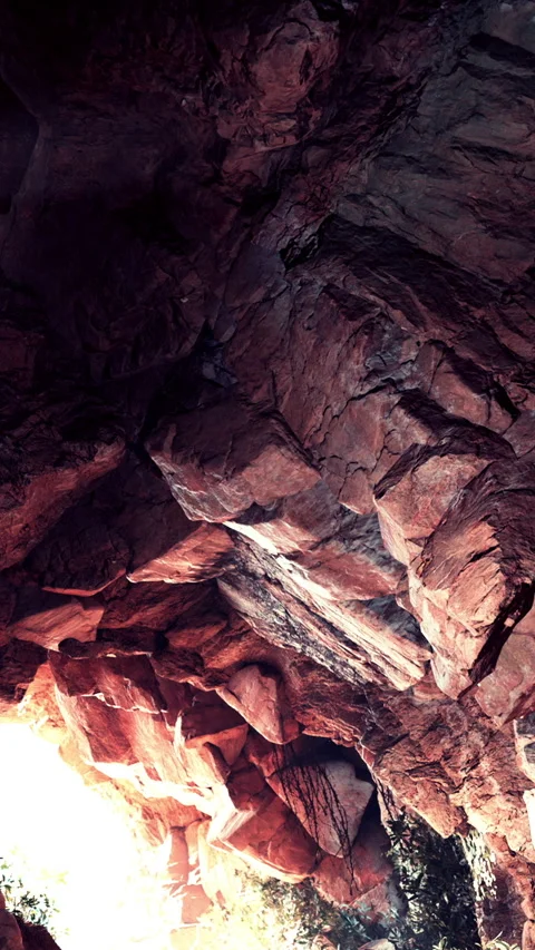 Exploring a rocky cave with light shining through the entrance in nature Stock Footage 339507831