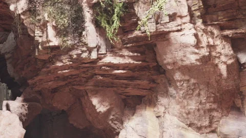 Exploring a rocky cave with natural formations and vegetation Stock Footage 339885191