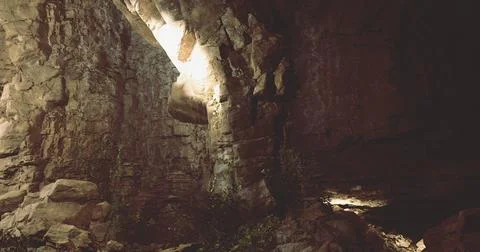 Exploring a rocky cavern with mysterious lighting in dim surrounds Ilustración de archivo
