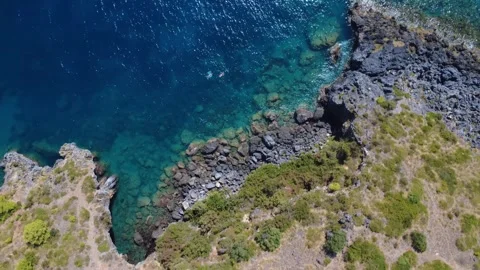Exploring a Rocky Coastline With Clear Blue Water and Lush Greenery in a Sunny Stock Footage 317763120