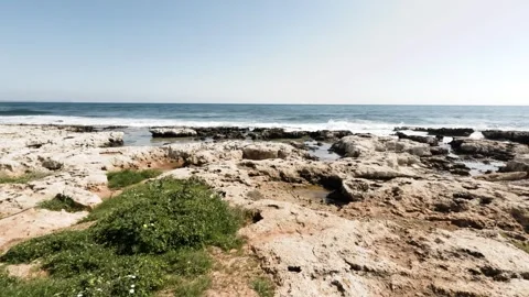 Exploring rocky coastline with clear ocean views in bright sunlight Stock Footage 302352231